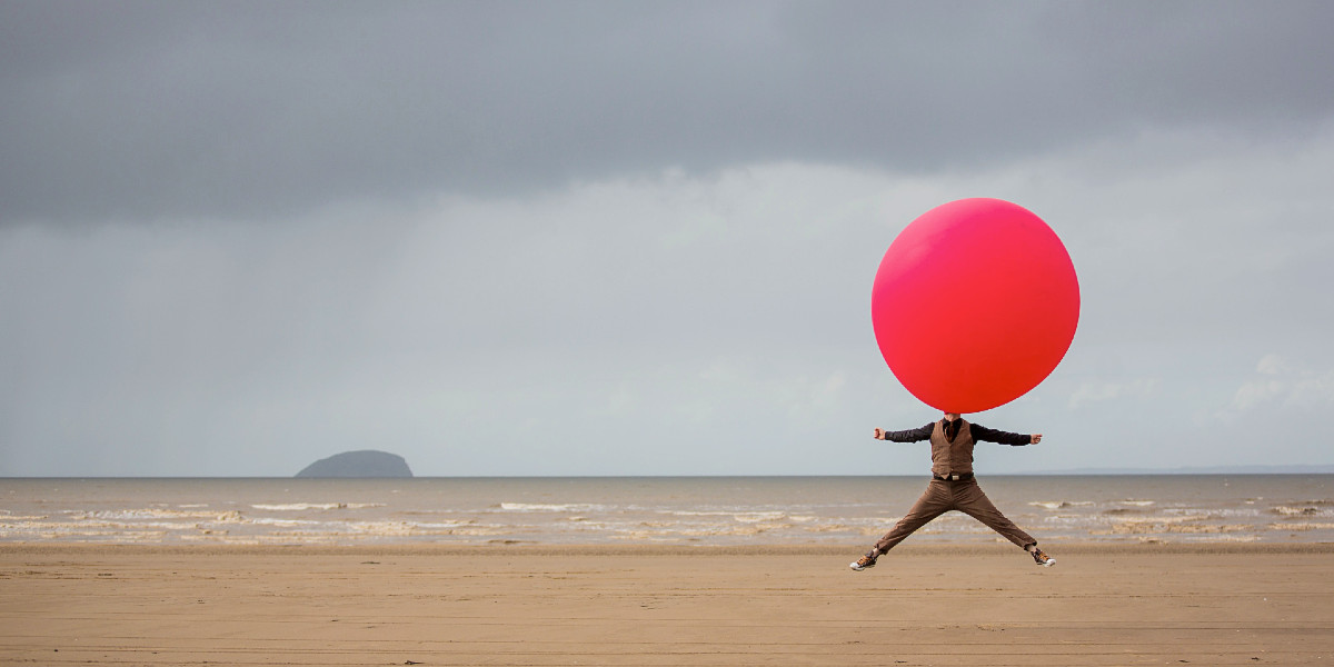 An image of a man with a giant balloon on the beach